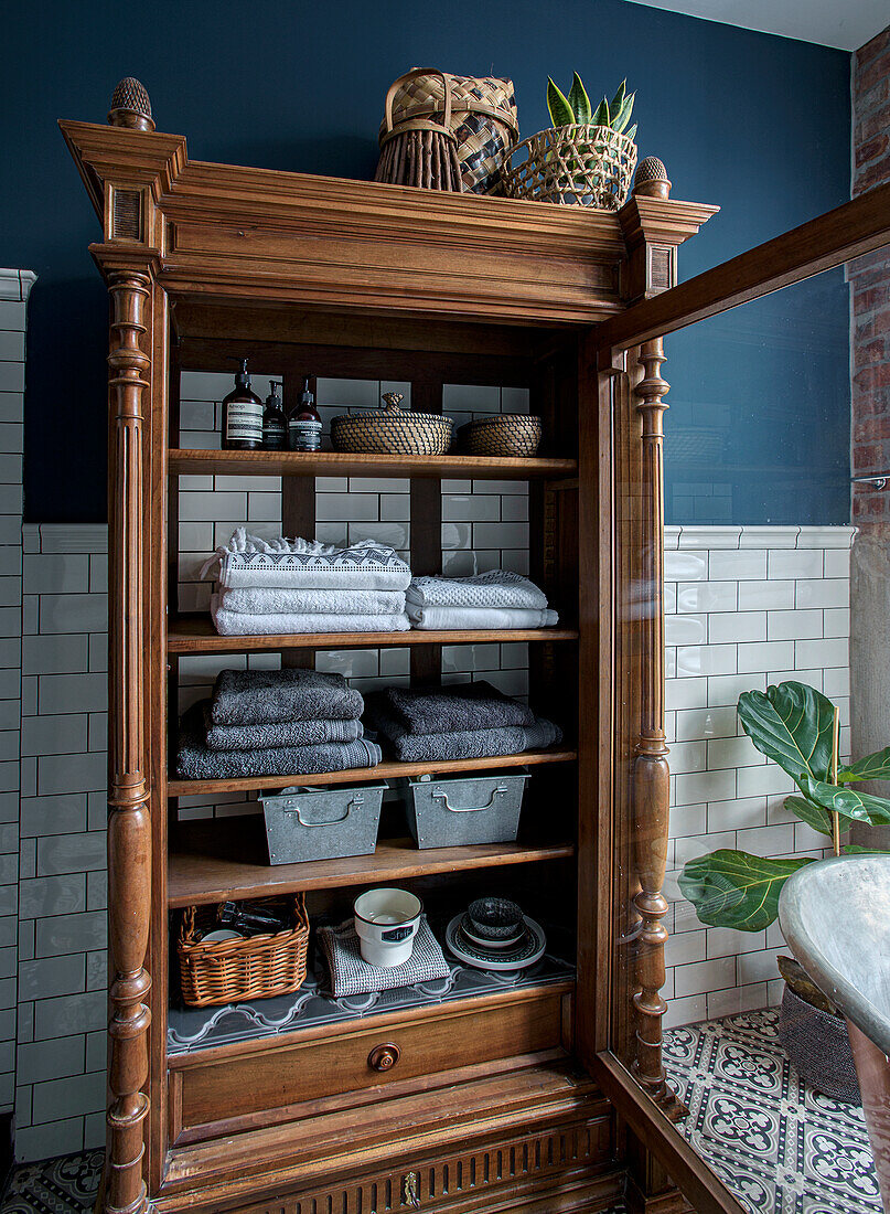 Traditional wooden cabinet with towels and baskets in the bathroom