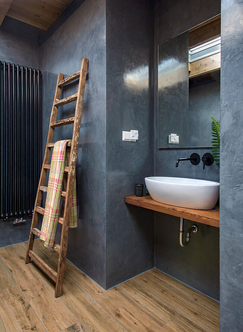 Modern bathroom with wooden ladder towel rail and washbasin on wooden top