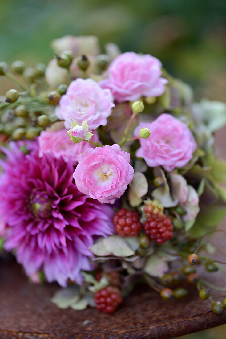 Spätsommerlicher Blumenstrauß mit Dahlien (Dahlia), Rosen, Hortensien (Hydrangea), Hagebutten und Brombeeren auf Metalltisch dekoriert