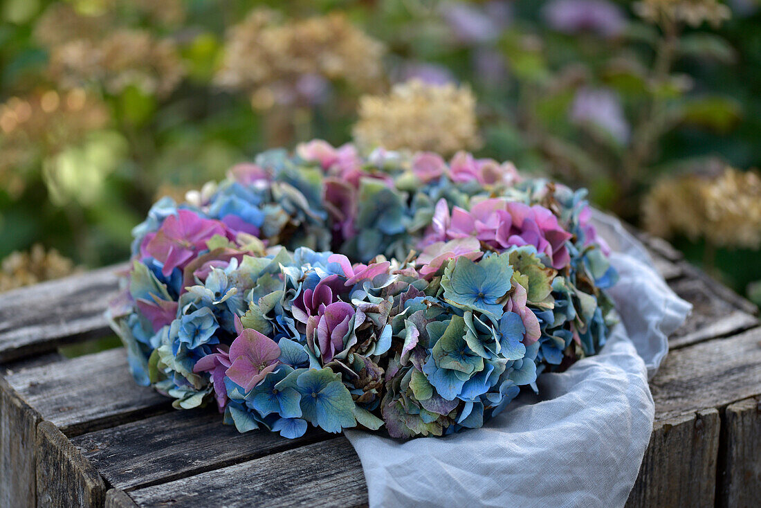 Colorful hydrangea wreath on a rustic wooden crate in the garden