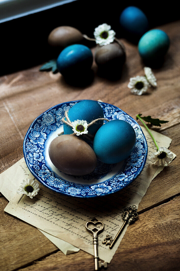 Blue and brown coloured Easter eggs on a blue vintage plate with flower decoration