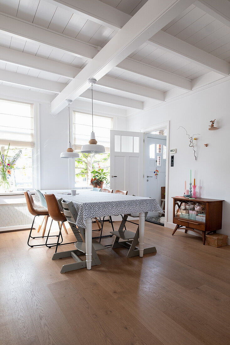 Bright dining room with wooden table, chairs and white-painted wooden beamed ceiling