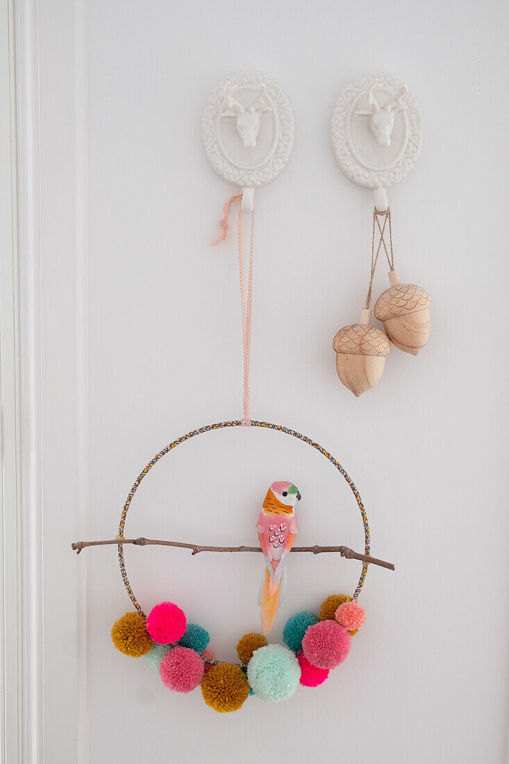 Parrot mobile with pompoms on plain white wall