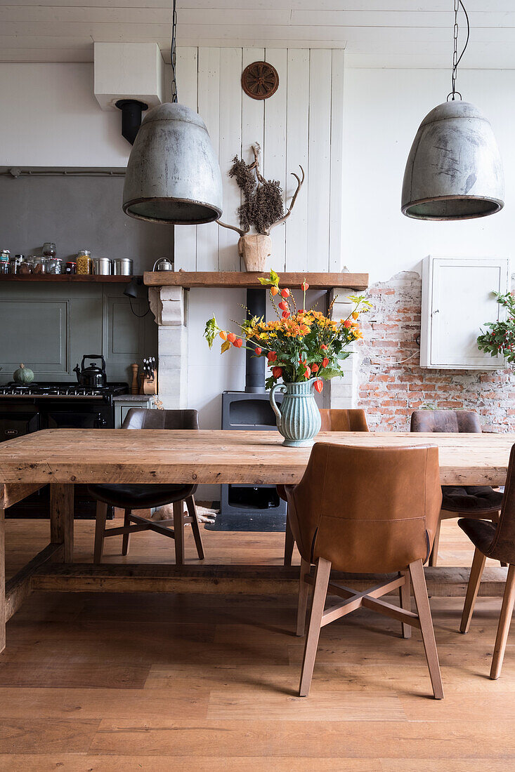 Esszimmer mit rustikalem Holztisch, Lederstühlen und Blumenstrauß in Keramikvase