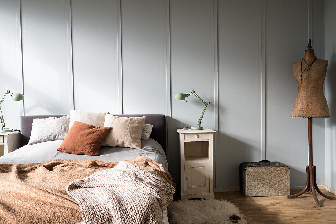 Minimalistisches Schlafzimmer mit Vintage-Schneiderpuppe, Doppelbett, Kissen und Decken