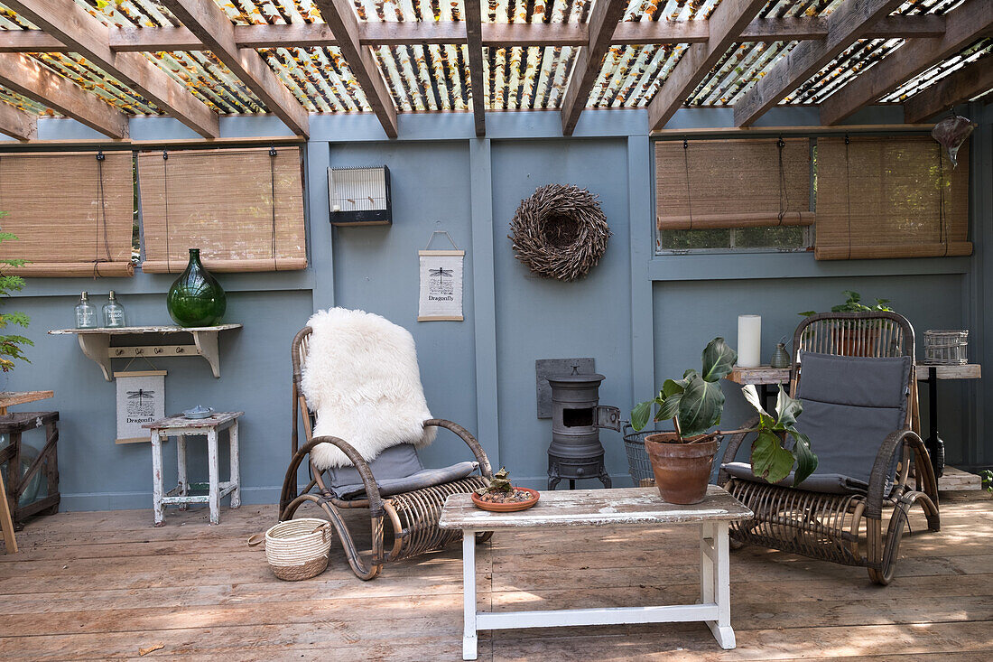 Covered terrace with rattan furniture and wood-burning stove