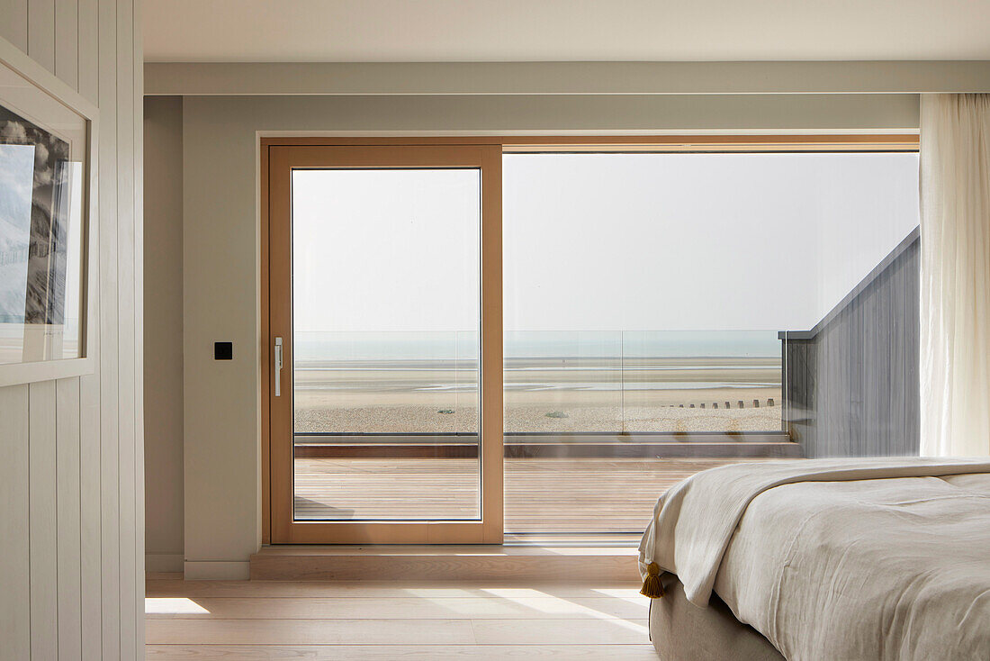 Schlafzimmer mit Blick auf den Strand durch große Fensterschiebetür