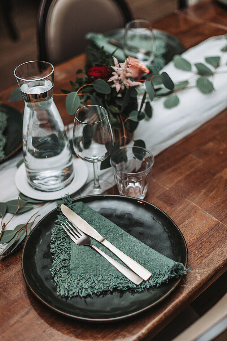 Table setting with dark plates and green napkins