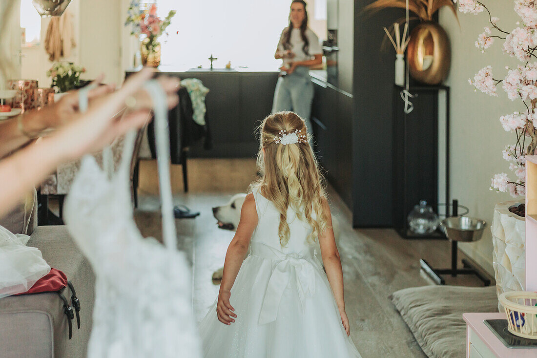 Girl in white festive dress being prepared for celebration in living room