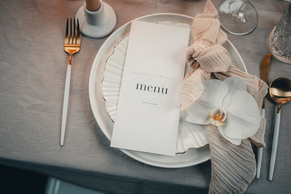 Elegant table decoration with menu card and orchid blossom