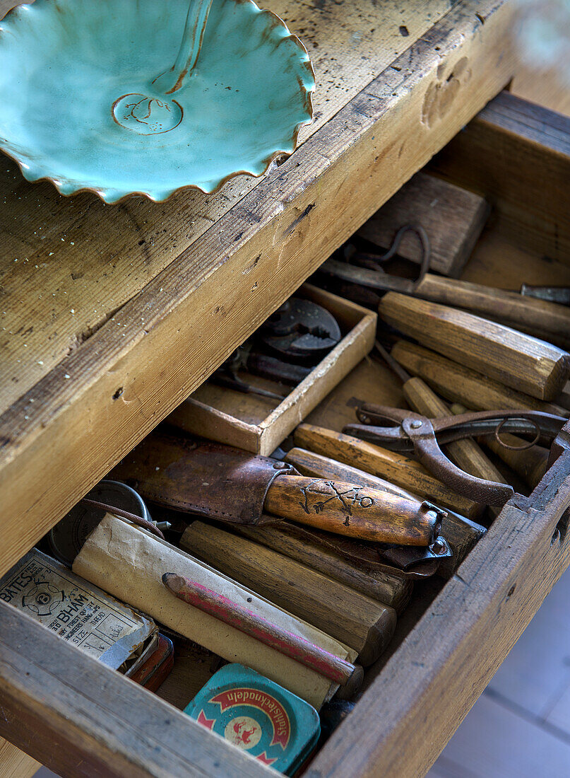 Open drawer with vintage tools and ceramic bowl