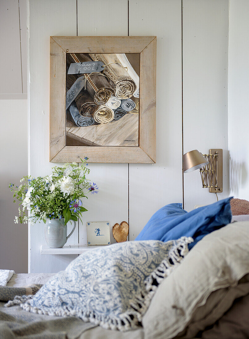 Wood-panelled bedroom with bouquet of flowers and picture