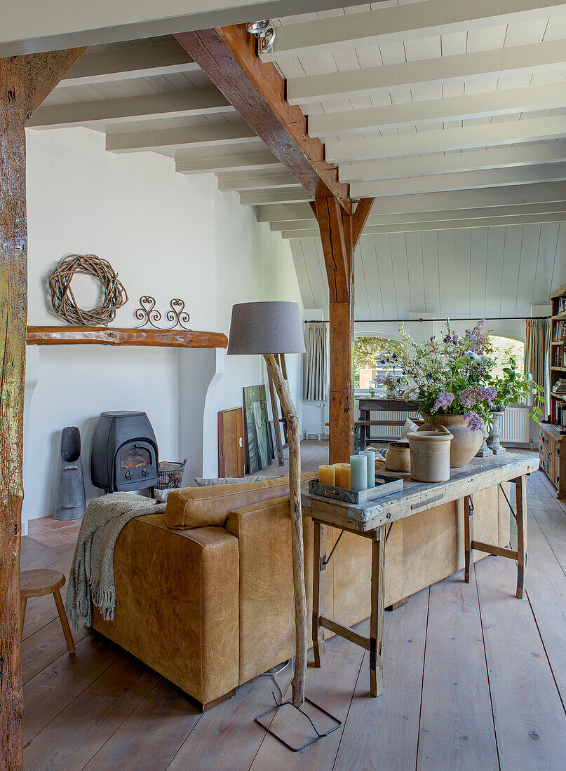 Living room with leather sofa, stove and wooden beams