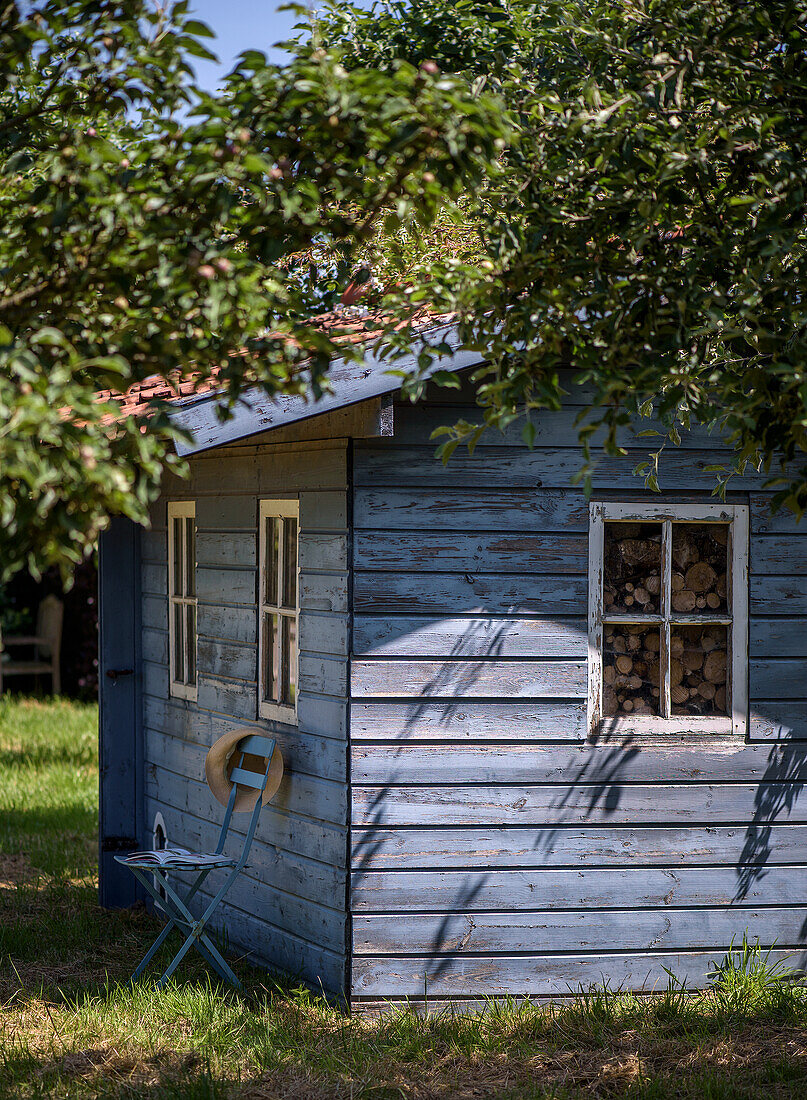 Blue-painted garden shed under trees