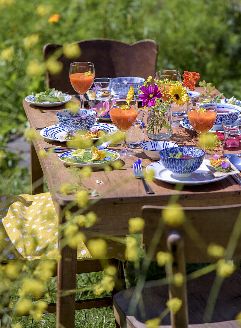 Wooden table set in the garden with colourful summer crockery and fresh drinks