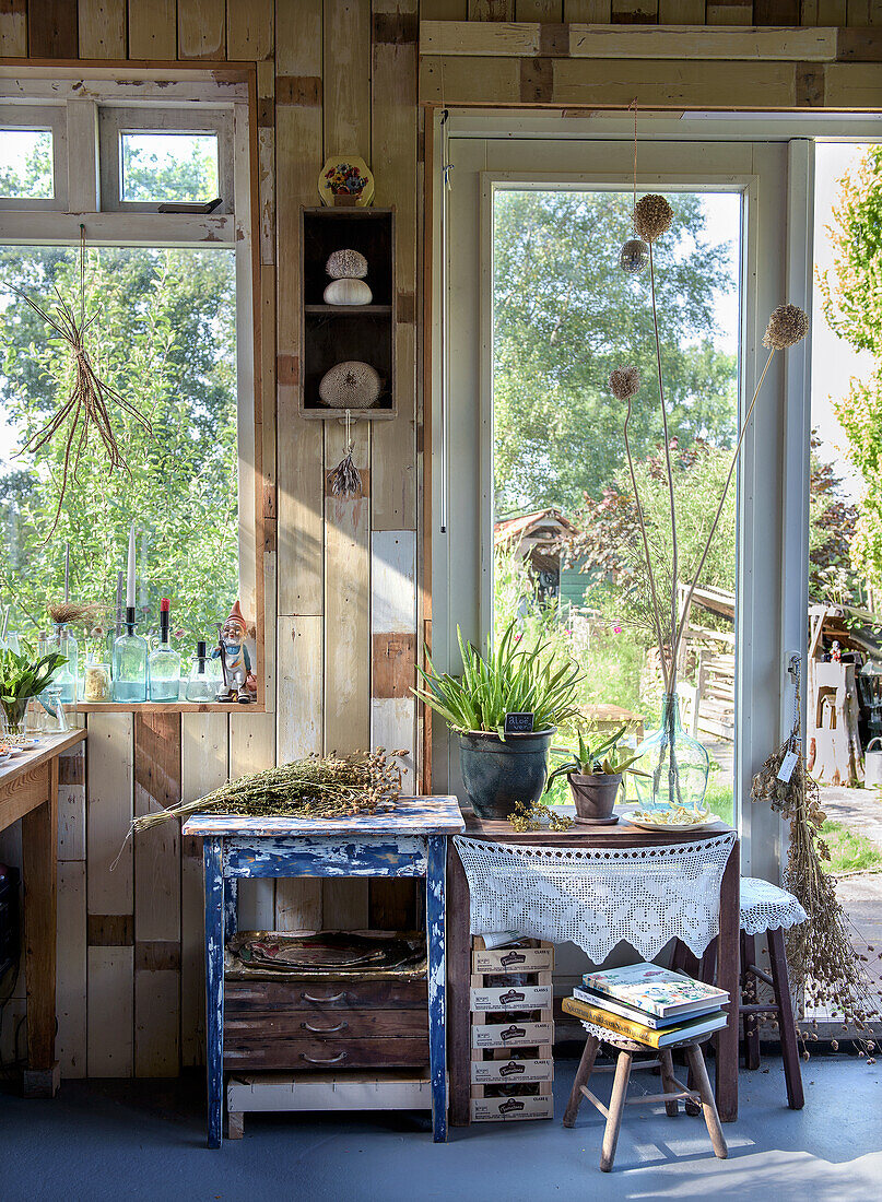 Sommergartenhäuschen mit Holzdekor, Pflanzen und Dekorationsartikeln am Fenster