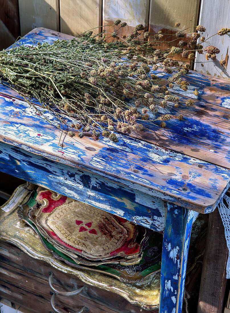 Trockenblumenstrauß auf blau bemaltem Vintage-Holzhocker