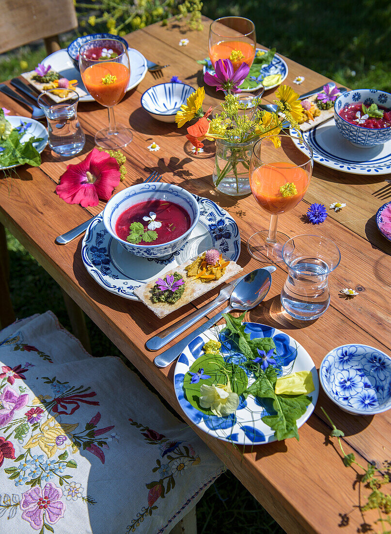 Wooden table set in summer garden with drinks and food