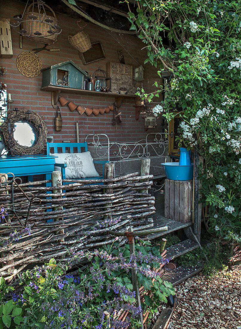 Cosy seating area with climbing plants and wicker fence in the garden