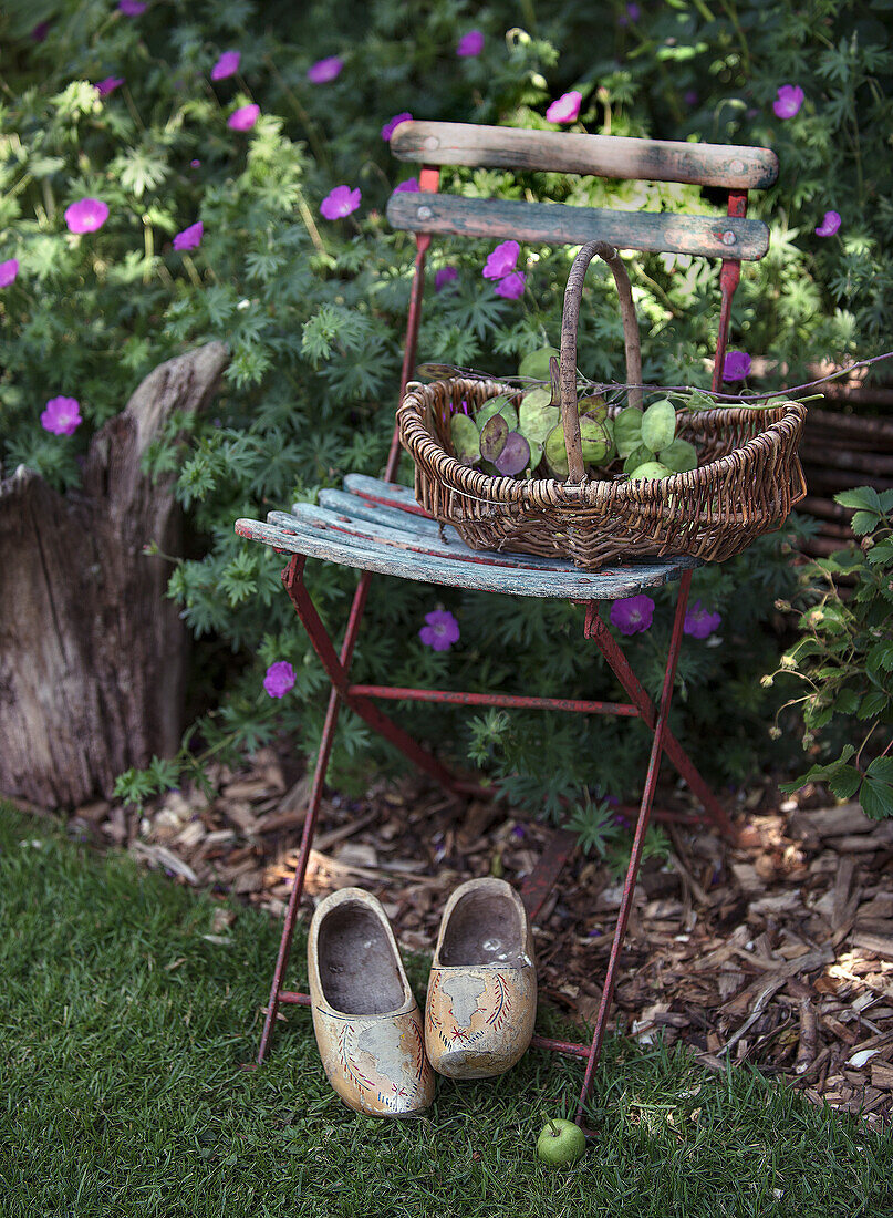 Decorative garden chair with wicker basket, silverware and clogs