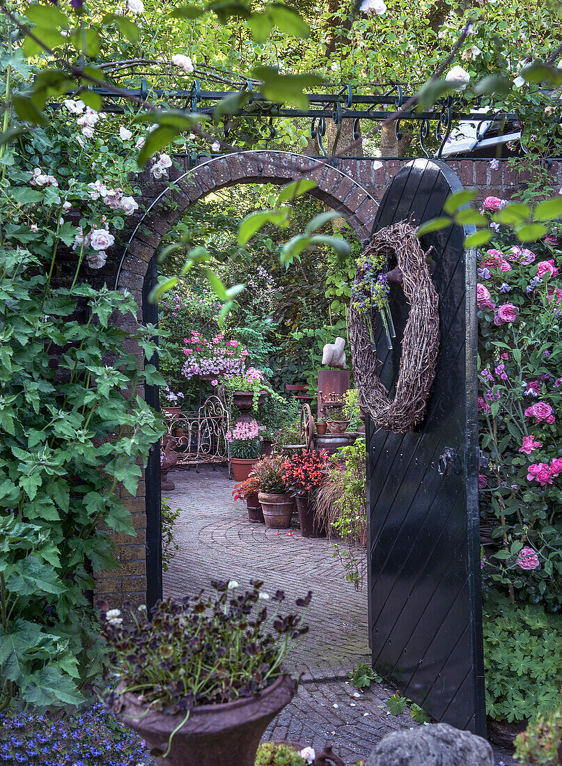 Romantischer Torbogen mit blühenden Rosengewächsen