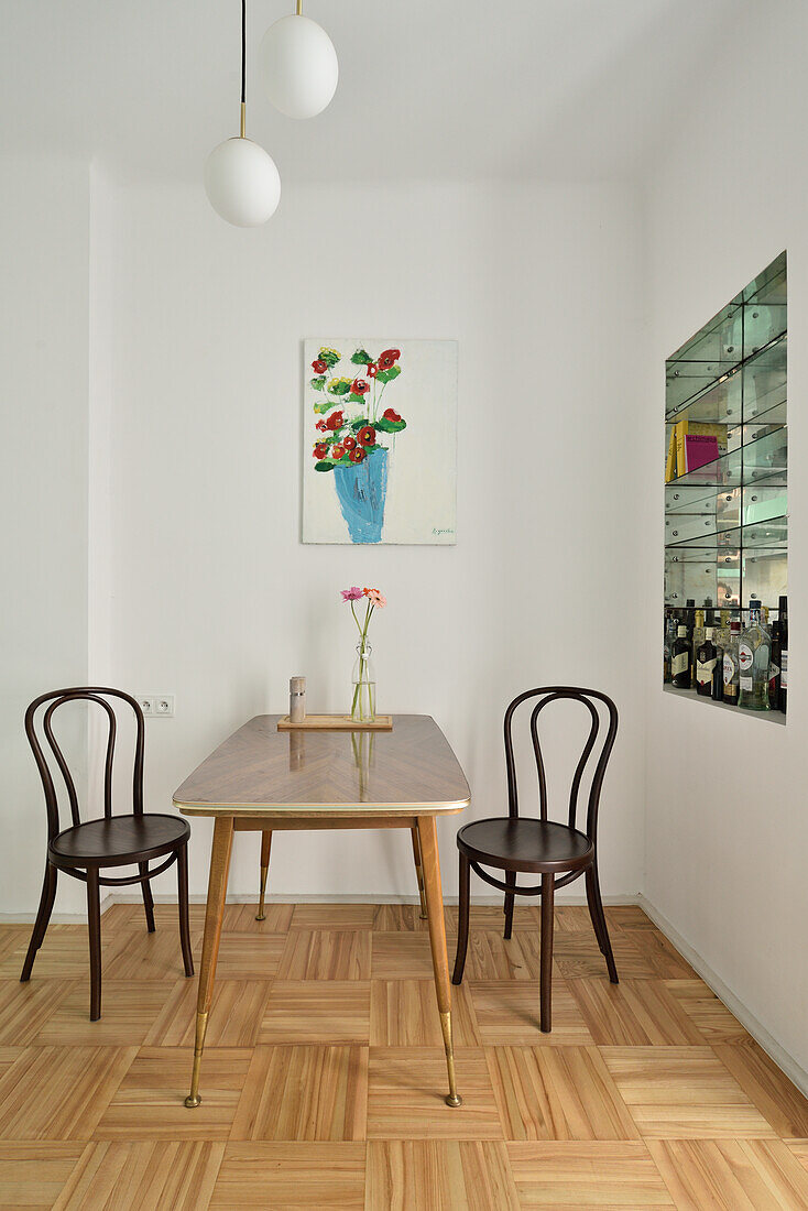 Dining area with wooden table and Thonet chairs and oil painting on the wall