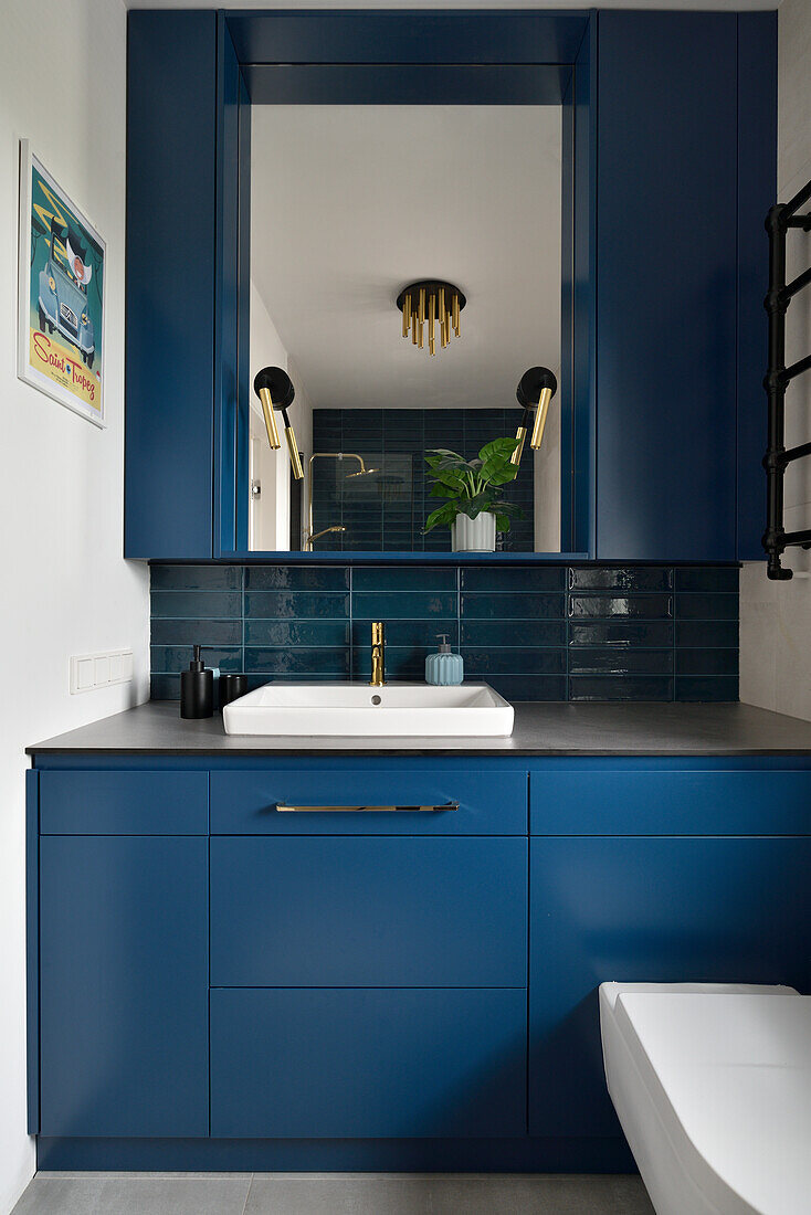 Bathroom with dark blue cabinets and gold-colored fittings