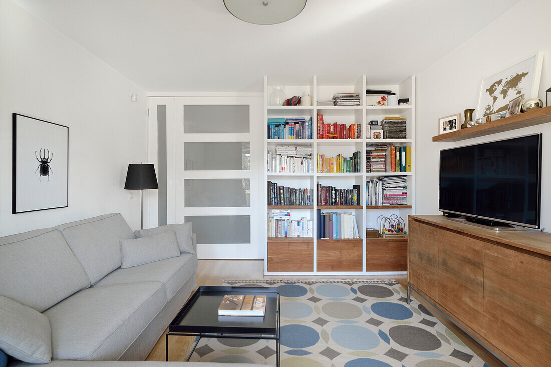 Living room with bookshelf, TV and patterned carpet