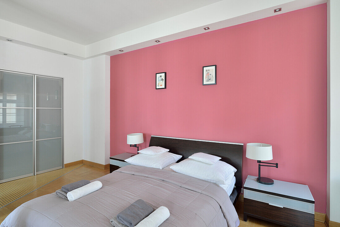 Modern bedroom with pink accent wall and dark bed frame