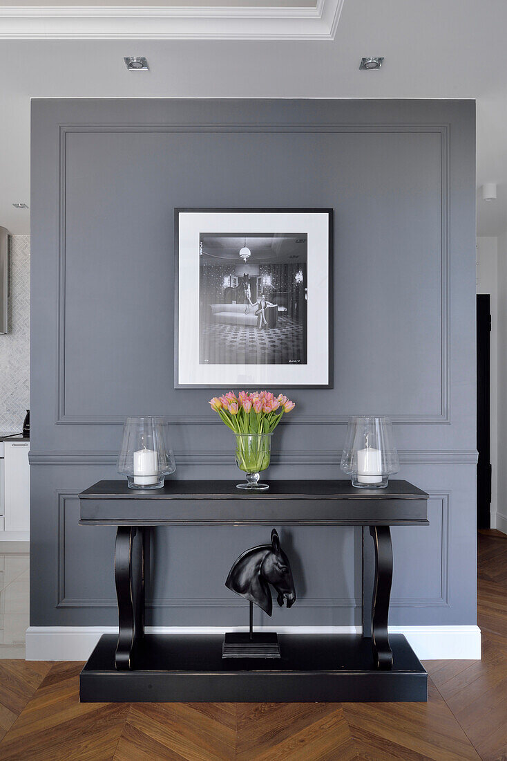 Grey wall paneling with console, photograph and bouquet of tulips