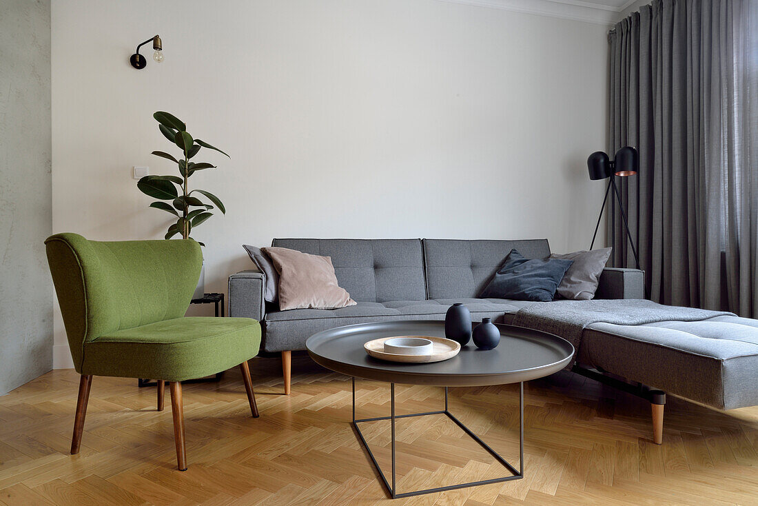 Wohnzimmergestaltung mit grauem Ecksofa und grünem Sessel