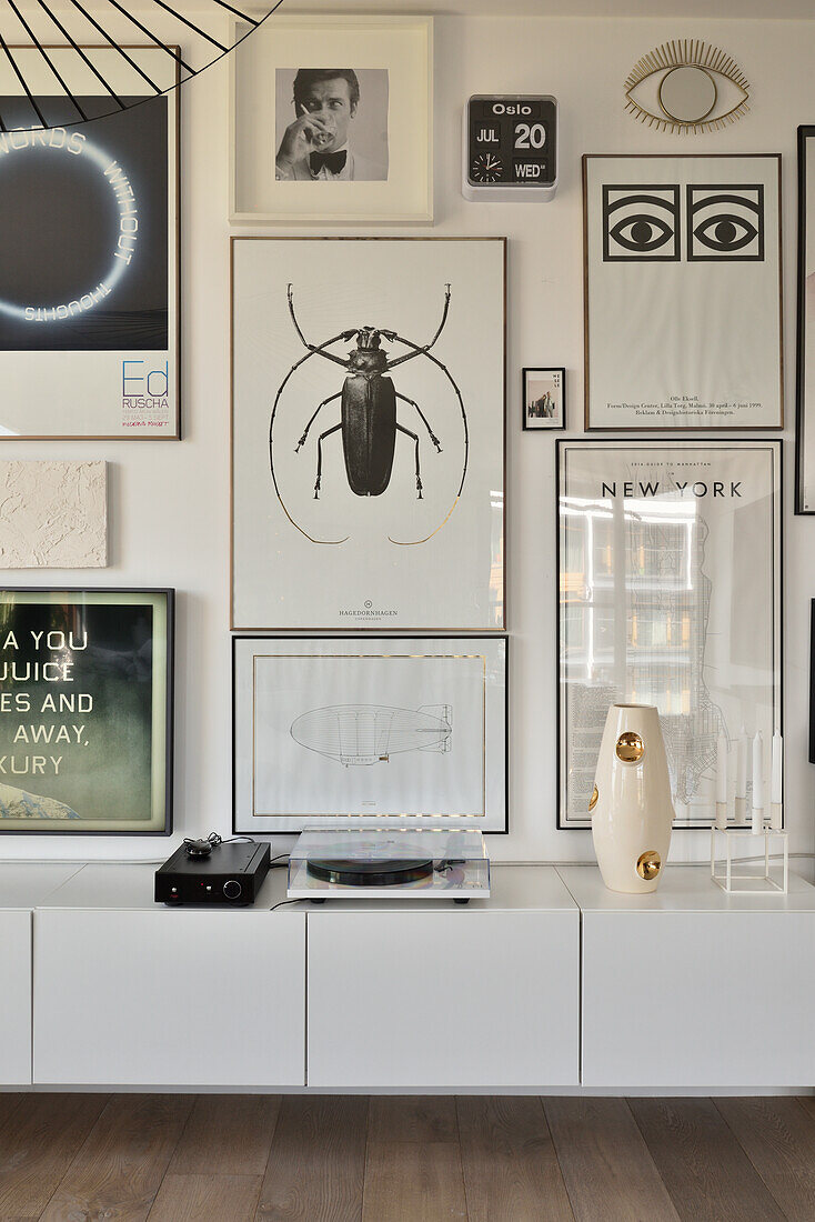 Wandgestaltung mit gerahmten Postern über modernem Sideboard mit Plattenspieler