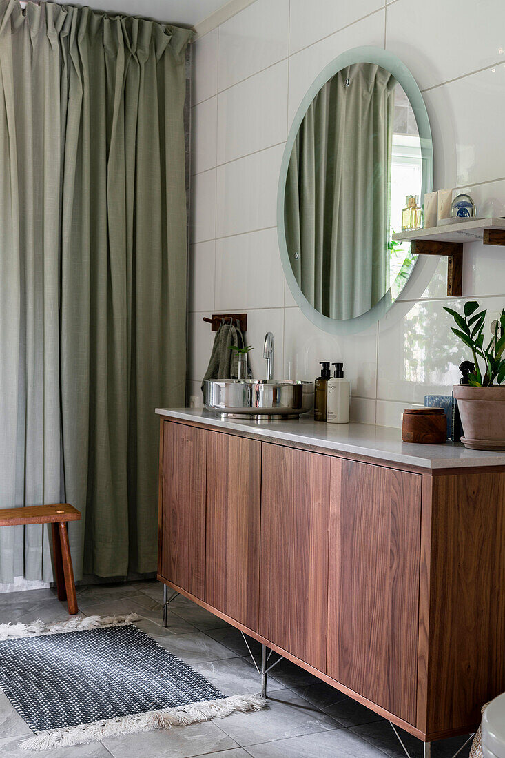 Modern wash area with wooden vanity unit and round mirror