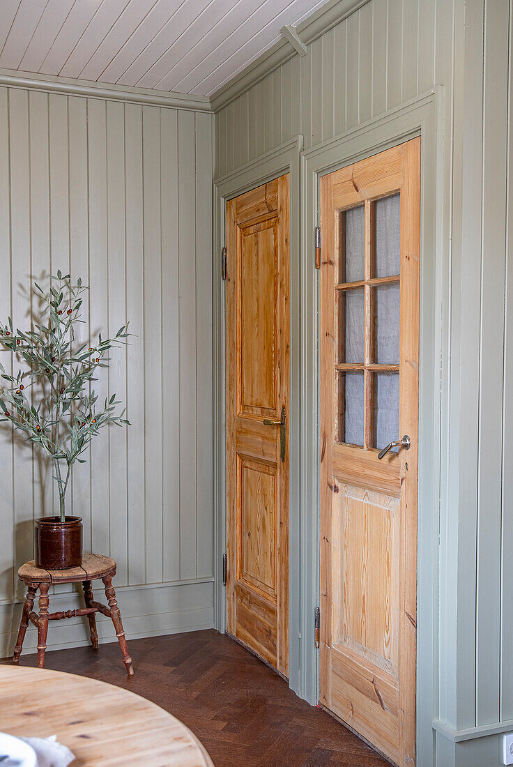 Zwei Holztüren mit unterschiedlichem Design in einem Raum mit Holzvertäfelung