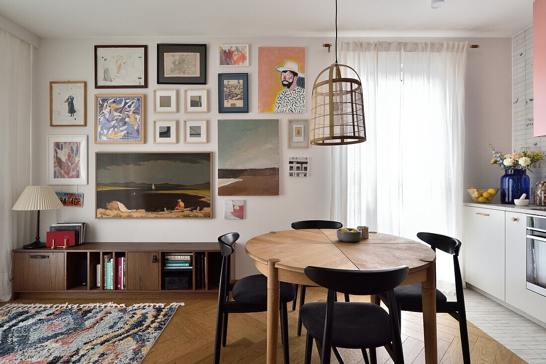 Dining area with round wooden table, black chairs and colourful picture wall