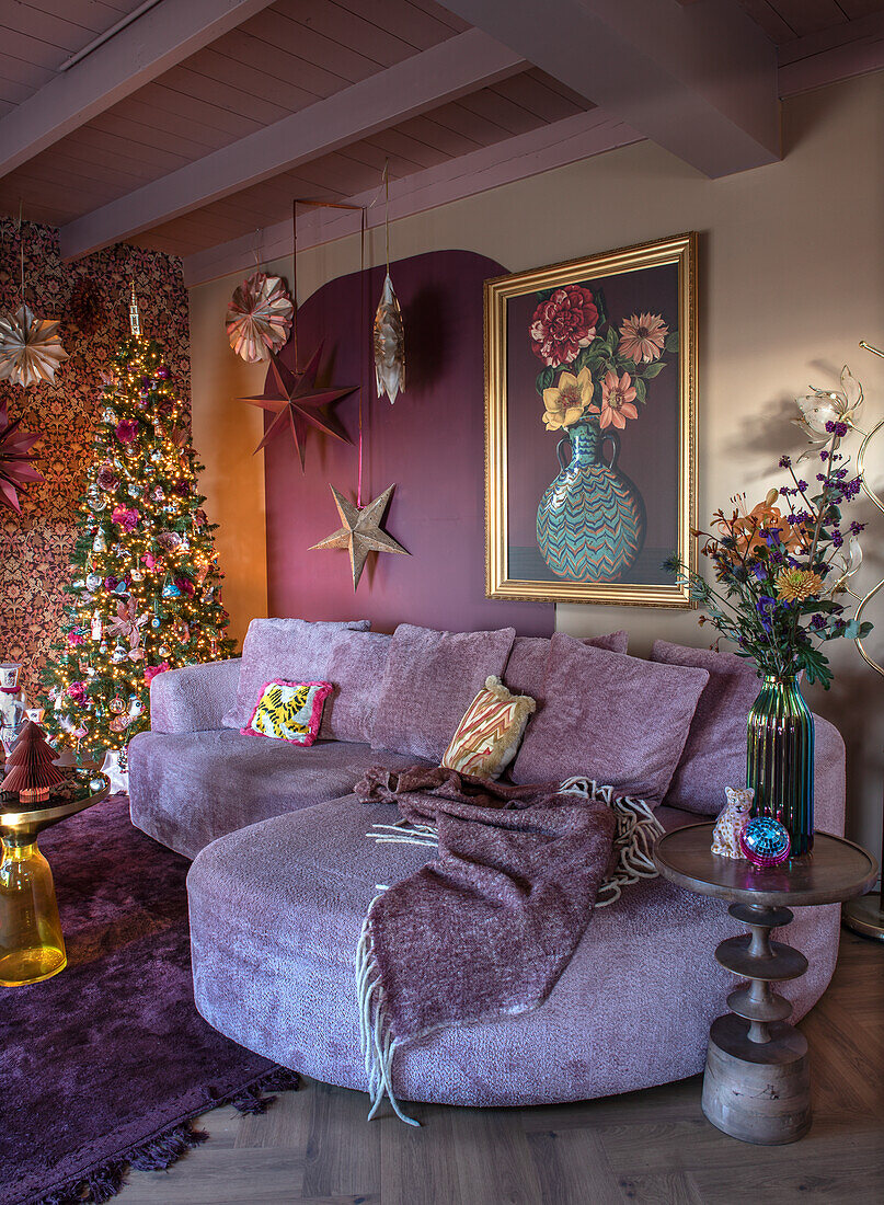 Living room with festively decorated tree and sofa area in light purple