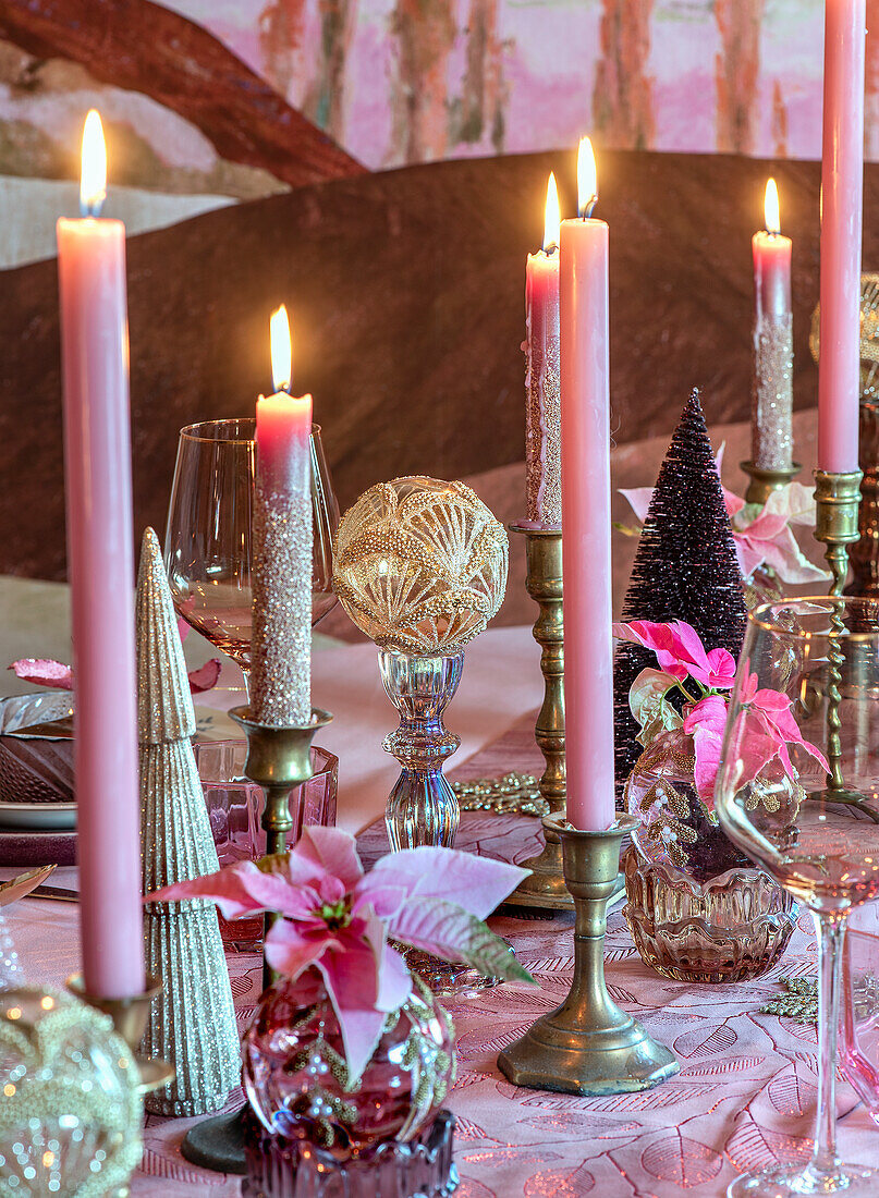 Weihnachtlich gedeckter Tisch mit rosafarbenen Kerzen und Blüten von Weihnachtssternen