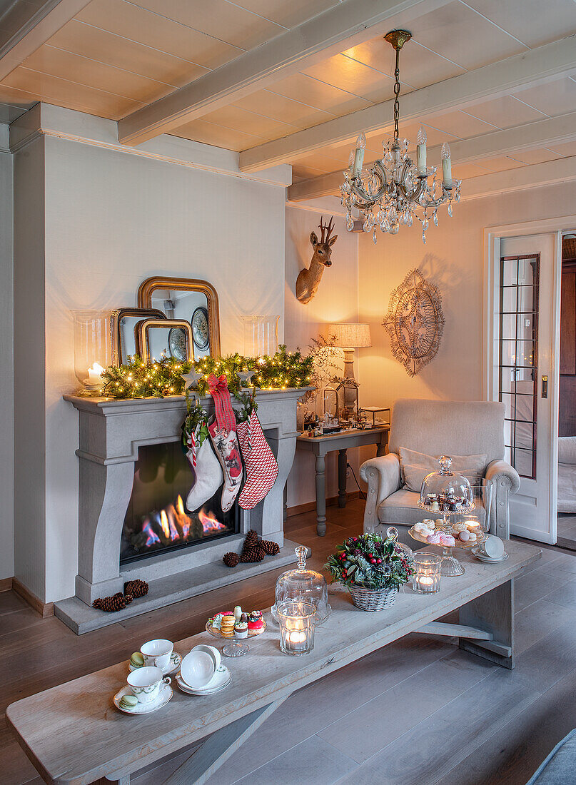 Weihnachtlich dekoriertes Wohnzimmer mit Kamin, Kristallkerzenleuchter und gedecktem Couchtisch