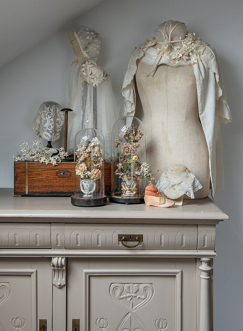 Vintage dressmaker's dummy and glass bells on an antique chest of drawers