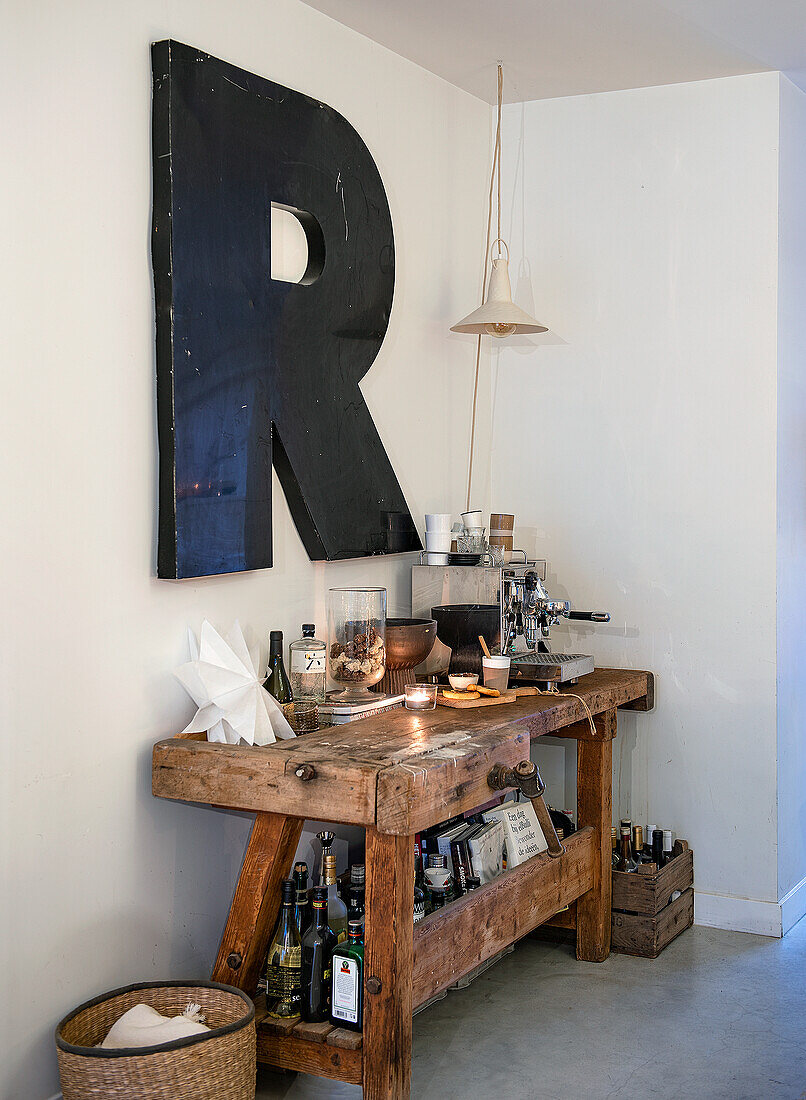 Bar-Bereich mit Werkbank, Kaffeemaschine und großem Buchstaben "R" an der Wand