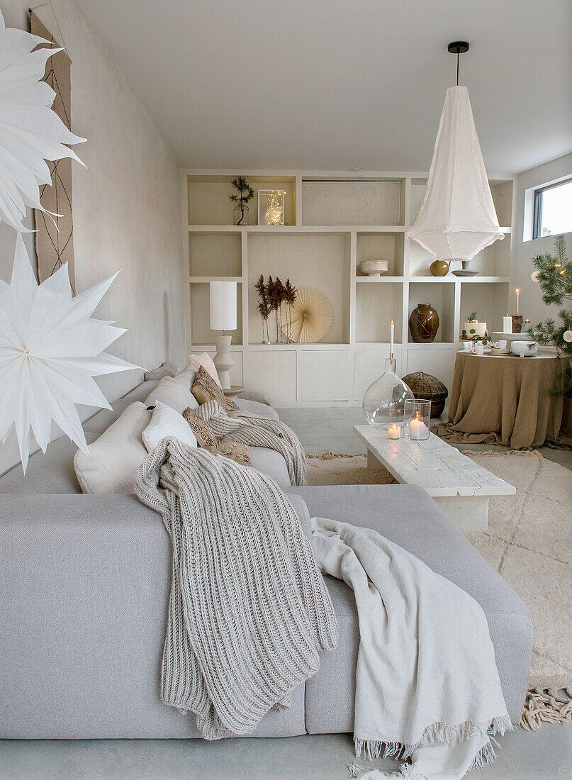 Open living area with grey sofa, white shelves and Christmas decorations