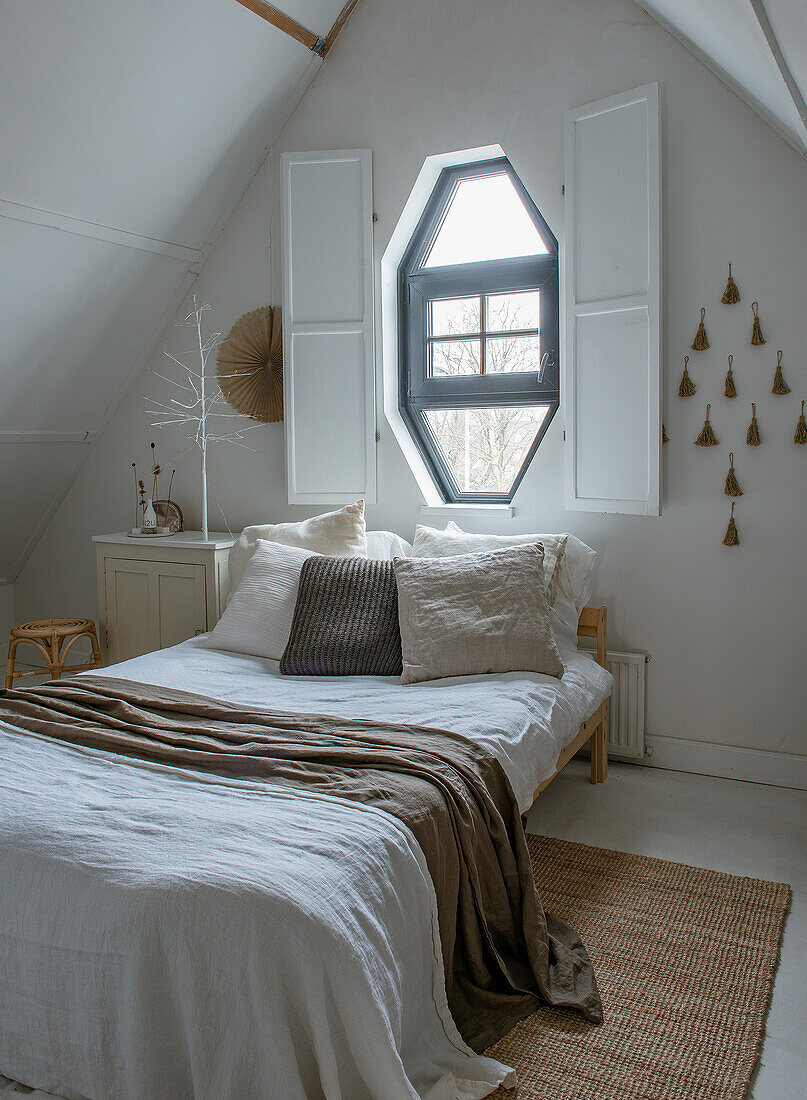 Schlafzimmer im Dachgeschoss mit achteckigem Fenster und Naturdeko