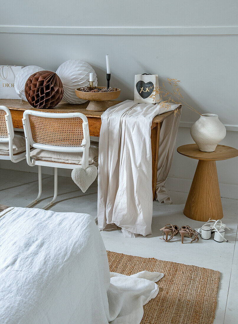 Bedroom with decorated wooden table, rattan chairs and white lanterns