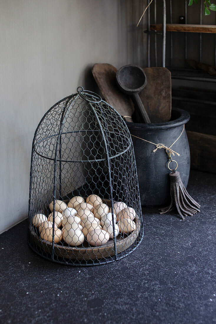 Wire basket with eggs on a black worktop in a rustic kitchen