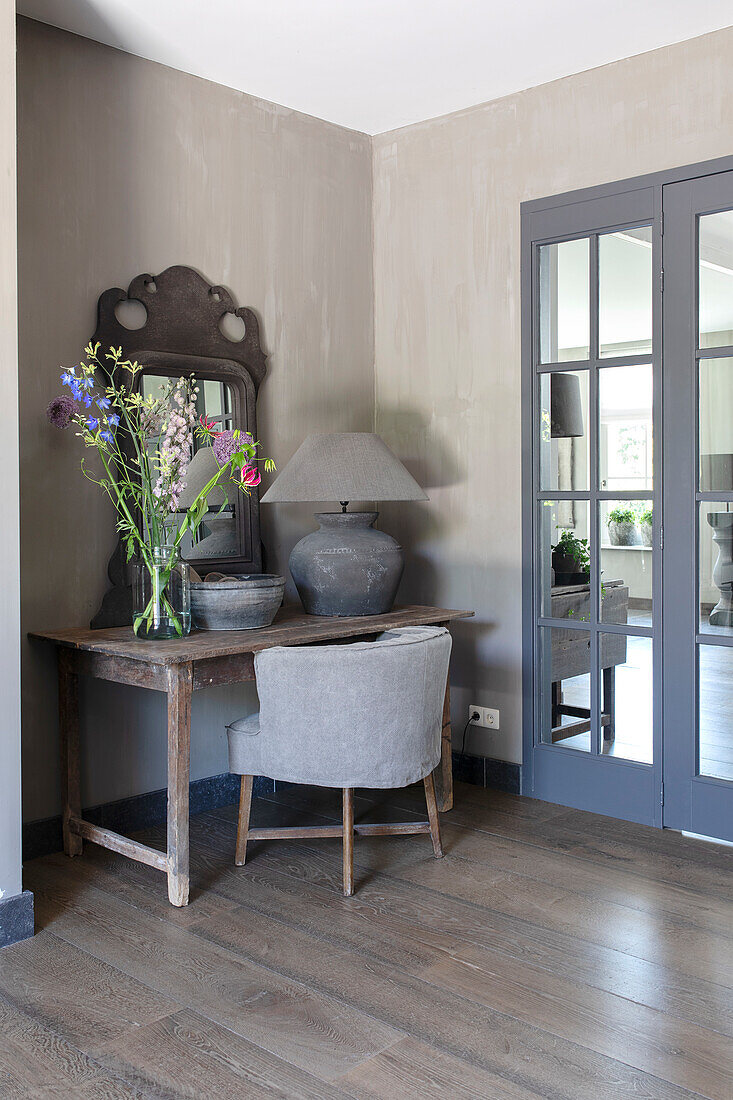 Rustic table with vase and mirror in room with wooden floor