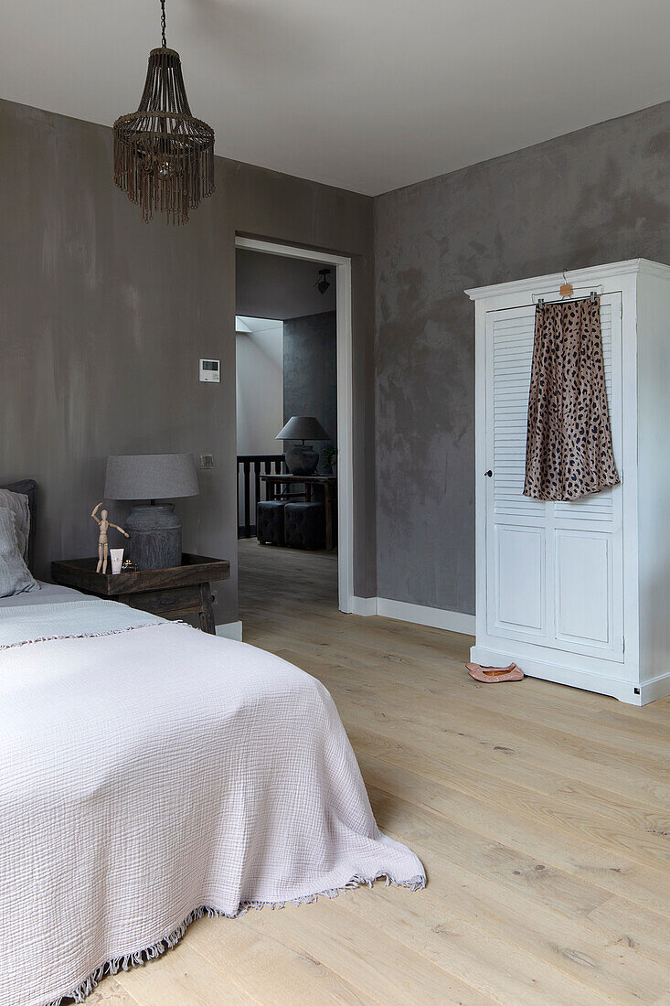 Bedroom with wooden floor, grey walls and hanging lamp