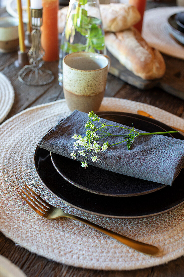 Rustic wooden table setting with black plates and linen napkin