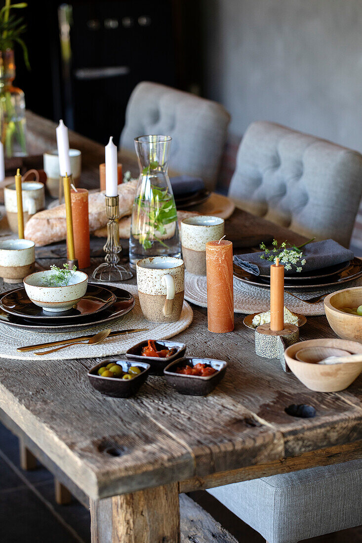 Rustic wooden table with candles and crockery in earthy colours