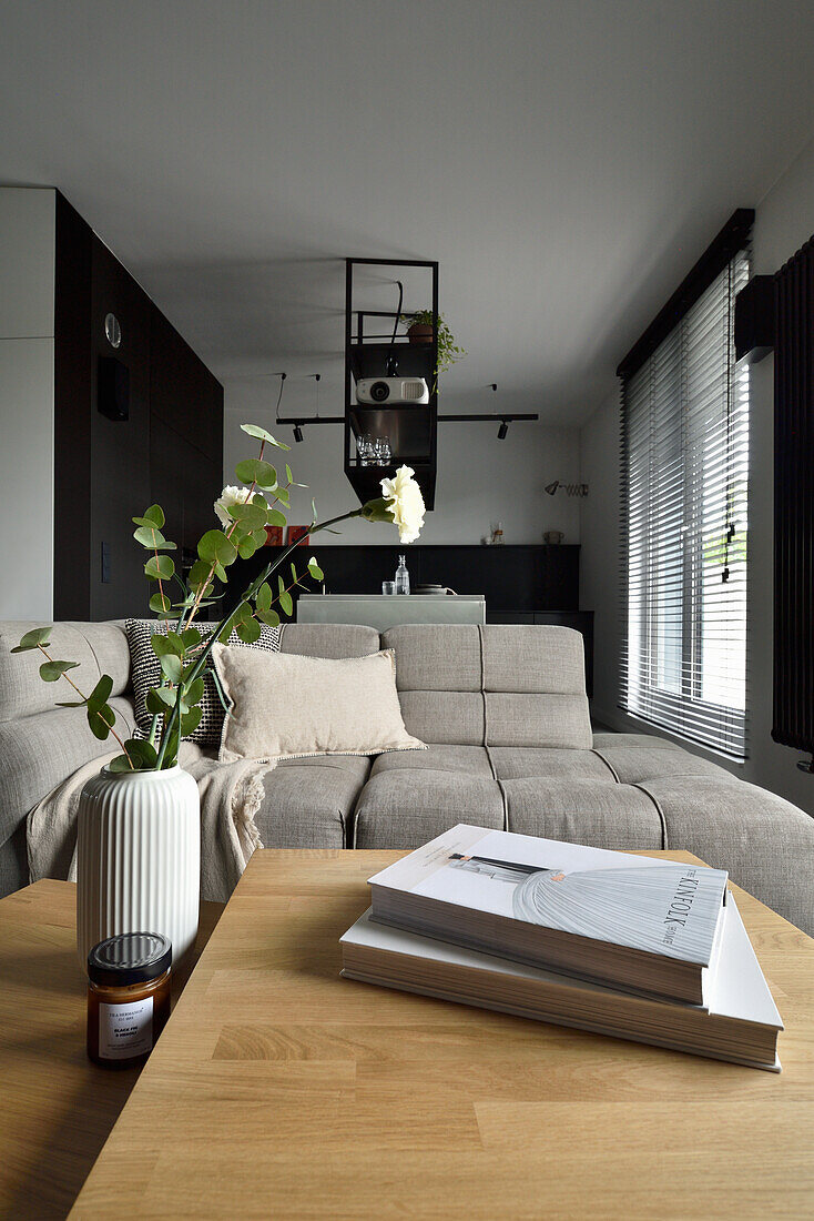 Living room with light grey couch and flower vase on a light wooden table