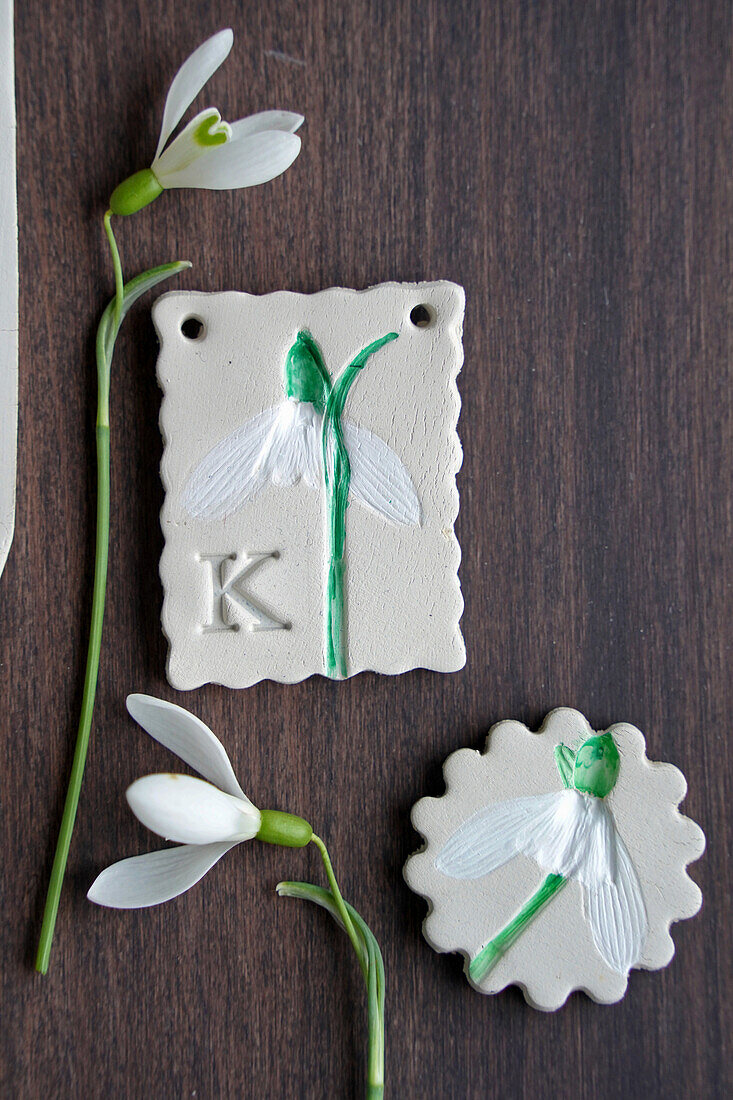 Homemade pendant with snowdrops and initials on a wooden table